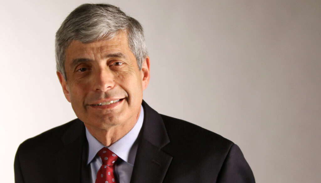 A man in suit and tie smiling for the camera.